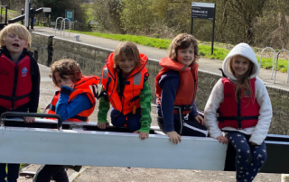 5 young people sit on a paddle of a canal lock
