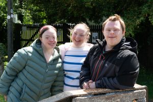 two young ladies and a young man smiling at standing next to a canal lock