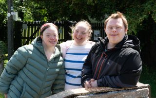 two young ladies and a young man smiling at standing next to a canal lock