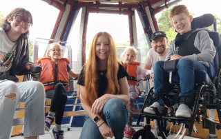 a family sitting in a canal boat, the young boy is a wheelchair user