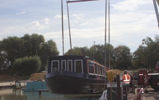 Canal boat being lifted into the water by crane.